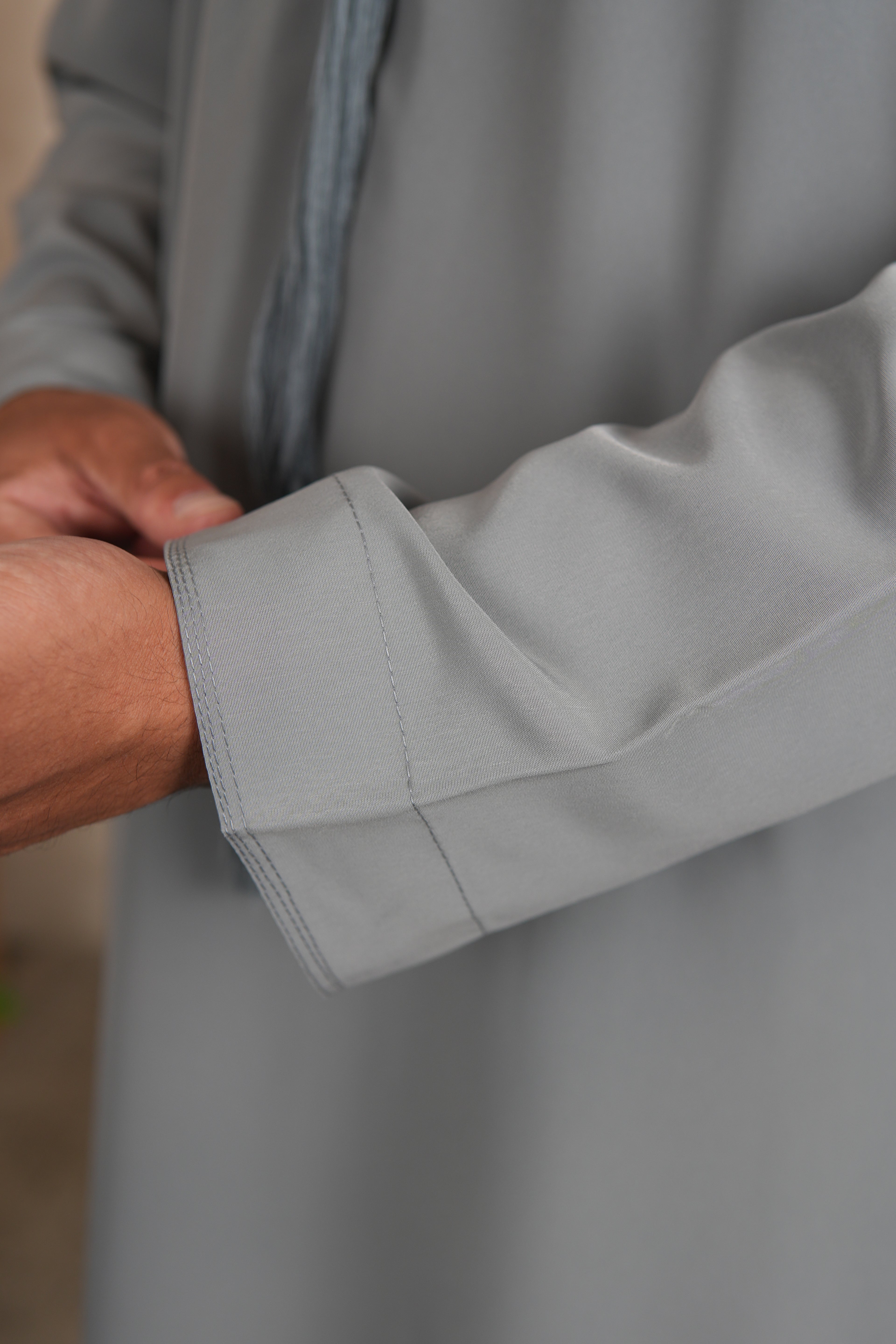 Close-up of a person wearing a gray shirt with rolled-up sleeve