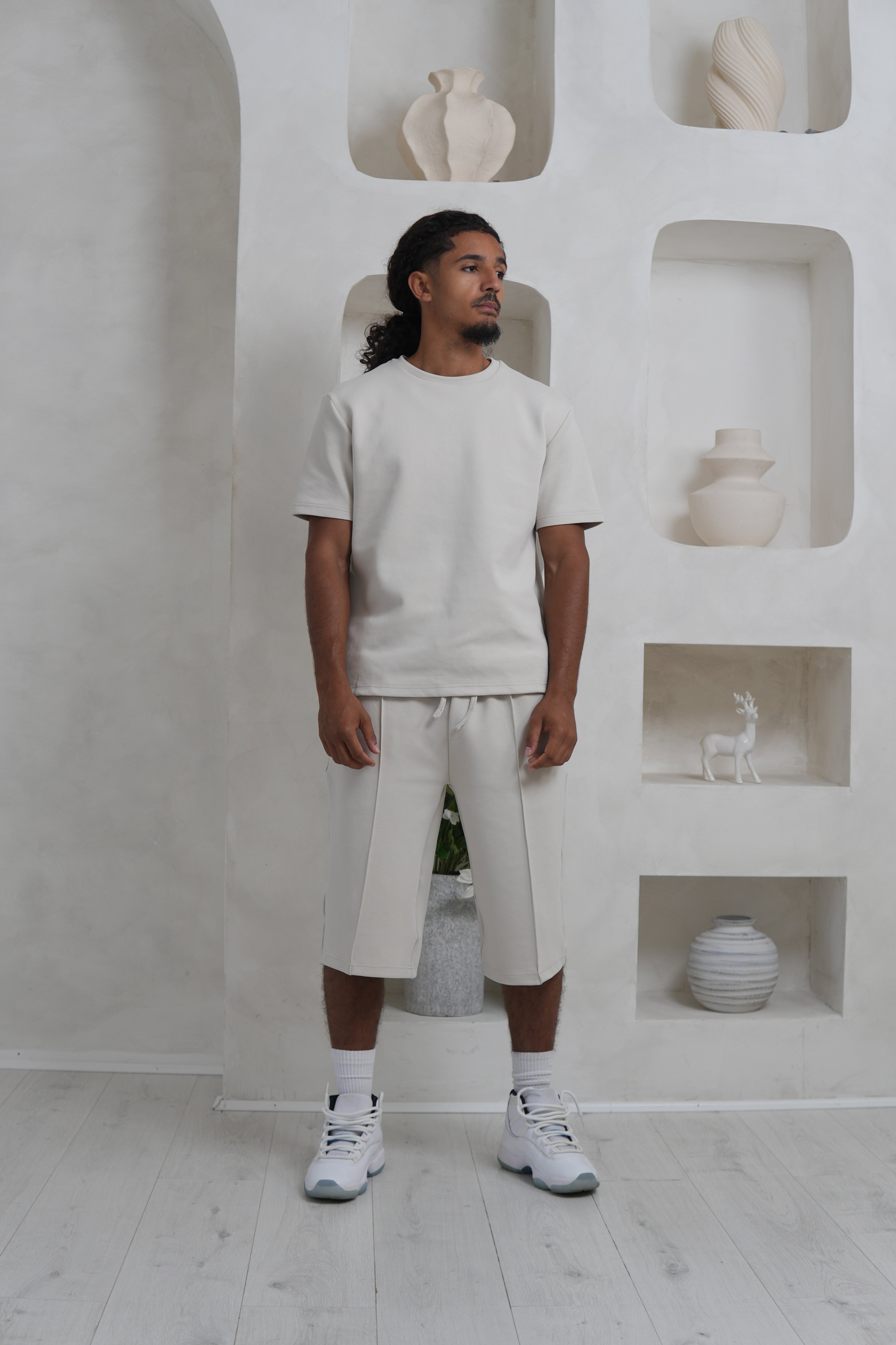 Person wearing a Cream outfit standing in a minimalistic room with white walls and floor. YAZIR