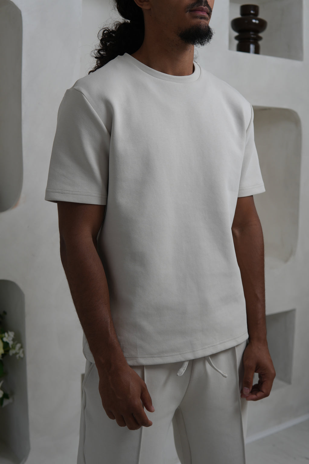 Person wearing a Cream t shirt in a minimalistic setting YAZIR