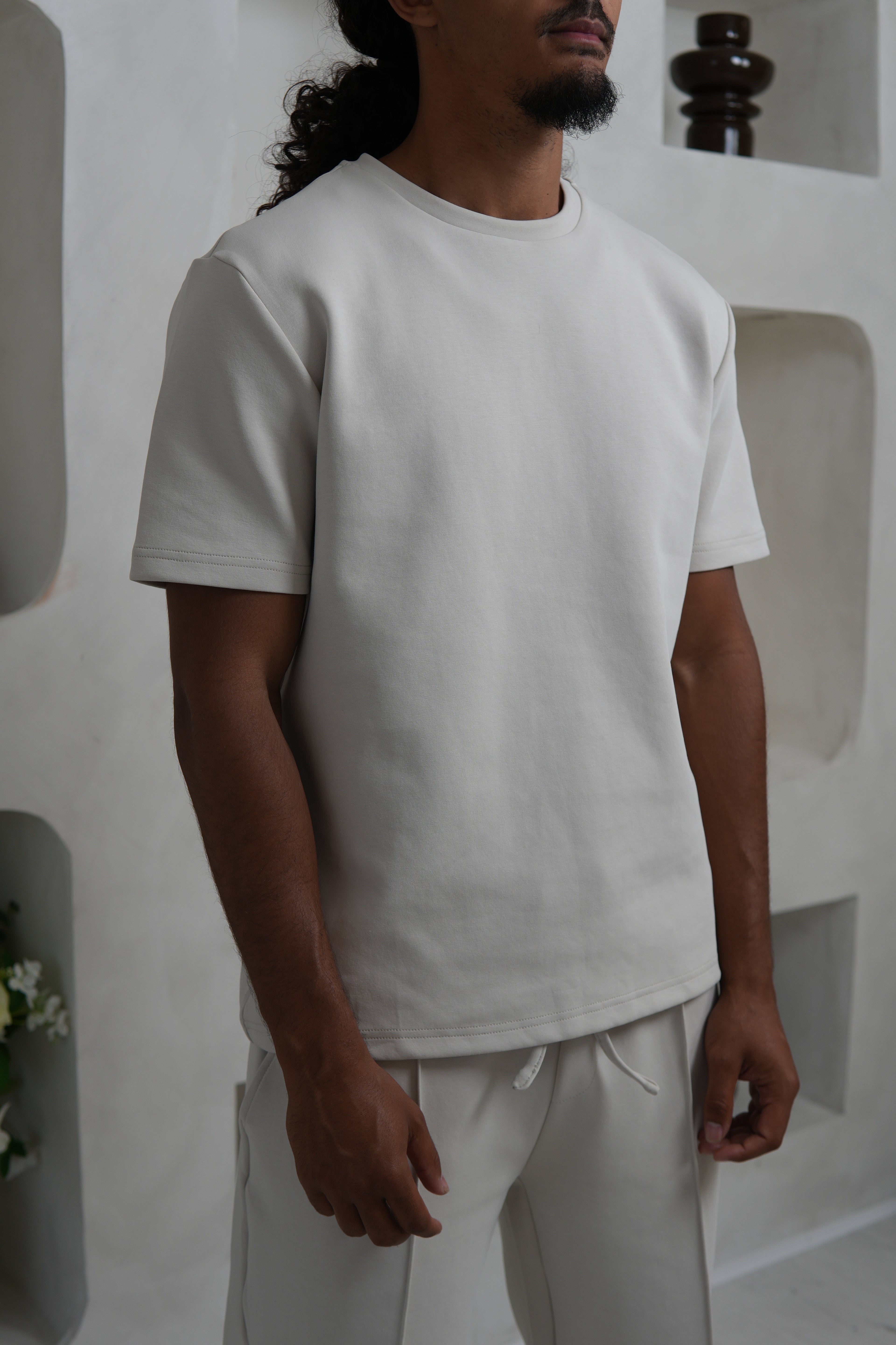 Person wearing a Cream t shirt in a minimalistic setting YAZIR