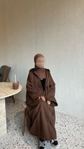 A long coat winter abaya, brown coloured, designed to keep you warm in the winter with a hoodie and a zip. Oversized size with strings on the hands to become cuffed.